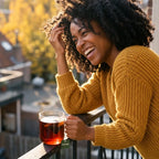 Smiling woman with healthy hair holding a cup of Five Black Beauty Tea