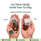 Hand holding a LunarSip Five Black tea bag of whole black herbs for healthy-looking hair next to a powdered tea bag