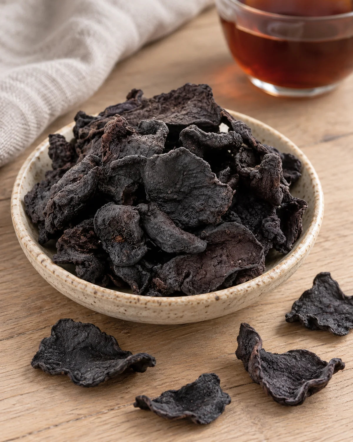 Thin curled slices of processed huang jing (Polygonatum sibiricum), steamed and sun-dried until black, in a ceramic dish