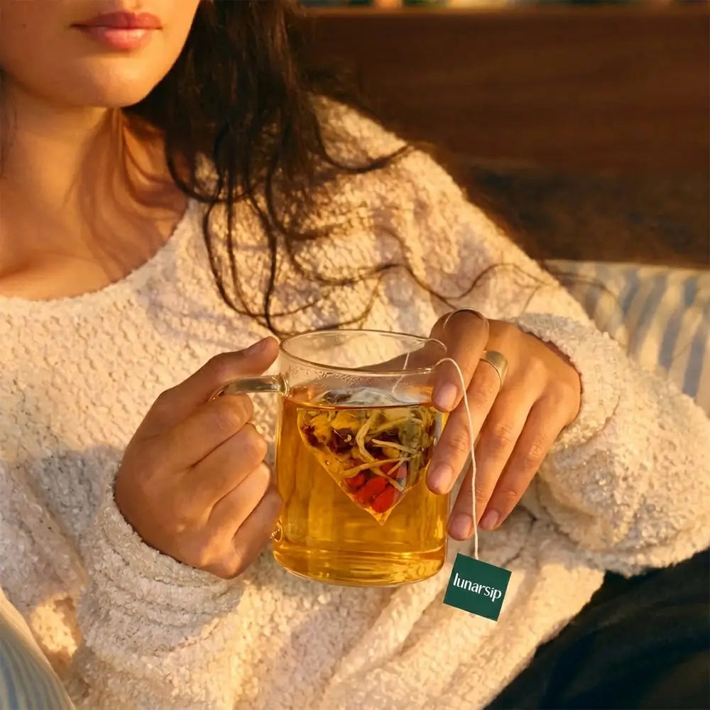 Woman drinking a cup of LunarSip Liver Detox Night Tea in the evening